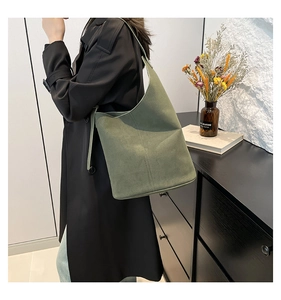 Detail of green suede shoulder bag featuring minimalist stitching and adjustable strap