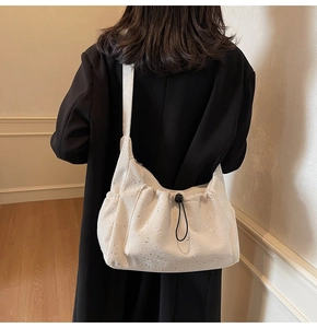 Detail of off-white corduroy shoulder bag with silver sequins and drawstring closure