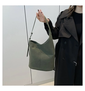 Detailed close-up of olive green suede bucket bag featuring vertical stitching and adjustable strap