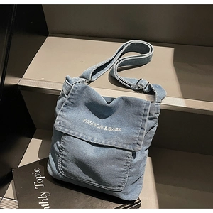 Dettaglio borsa a tracolla in denim con patta e scritta FASHION & BAGS decorativa