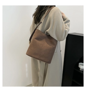 Brown suede bucket bag with adjustable strap shown worn on model for size and style