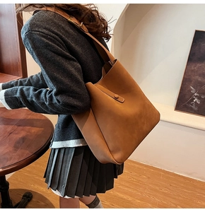 Detail of caramel suede shoulder bag with metallic clasp and minimalist strap design