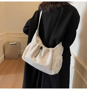 Detail of cream-colored pleated nylon crossbody bag with side pocket and drawstring
