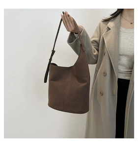 Detail of dark brown matte shoulder bucket bag with adjustable strap on a model