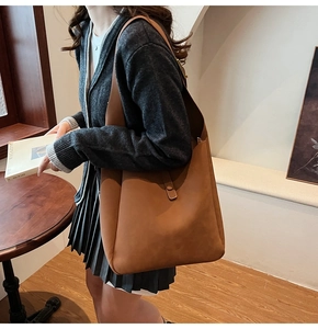 Close-up of brown textured leather hobo bag with wide strap and snap closure detail
