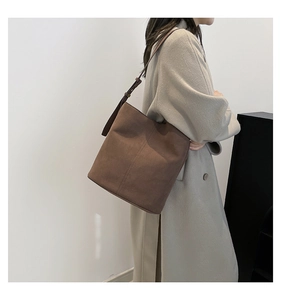 Deep brown suede bucket bag featuring adjustable strap and vertical seam details