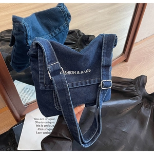 Riflesso a specchio che mostra i dettagli della borsa a tracolla in denim blu ricamata