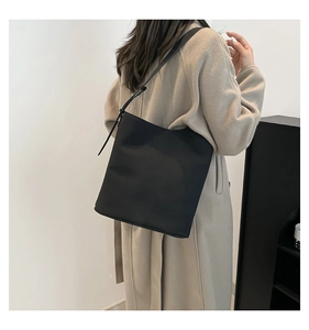 Detailed view of the black minimalist leather bucket bag with adjustable shoulder strap