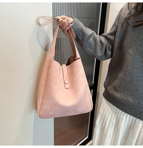 Detailed macro view of pink suede shoulder bag with magnetic buckle and matte texture