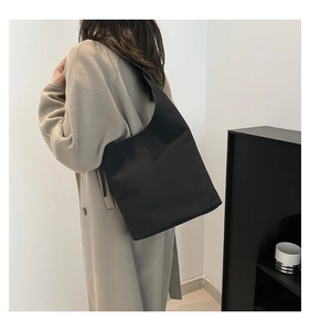 Detail of minimalist black nylon shoulder bag showing size and drape on female model