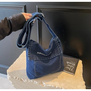Vista dettagliata della trama in denim blu e della stampa bianca sulla borsa a tracolla