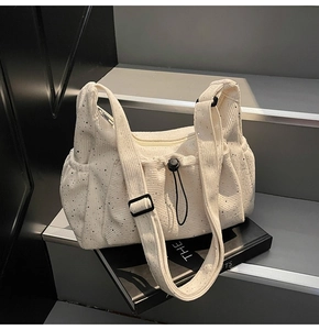Detail of off-white corduroy crossbody bag featuring silver glitter and drawstring pocket
