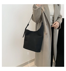 Detail of adjustable buckle strap and sleek minimalist leather hobo bag on model