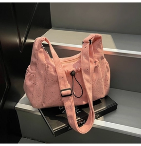 Detail of pink corduroy shoulder bag featuring silver sequins and black drawstring buckle