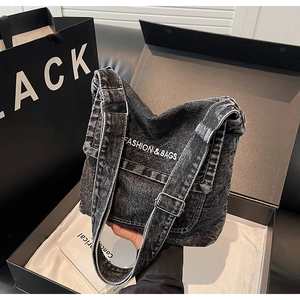 Dettaglio della borsa a tracolla in denim nero lavato con tracolla regolabile e logo