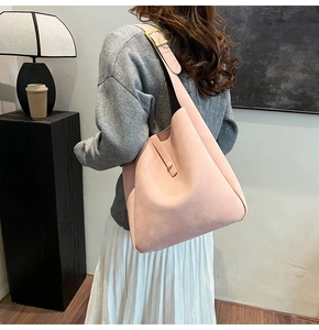 Detailed close-up of a pink suede hobo bag with a gold buckle and latch closure