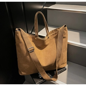 Detail of dark brown canvas tote bag with adjustable strap and vintage metal buckles