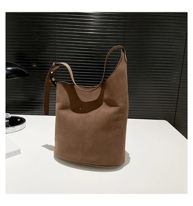 Detail view of large dark brown suede bucket bag with adjustable strap and metal buckles