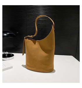 Detail of mustard yellow asymmetrical bucket bag with adjustable strap and oval base