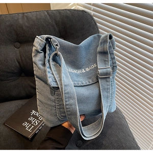 Dettaglio della trama in denim blu chiaro e della scritta bianca sulla borsa a tracolla alla moda