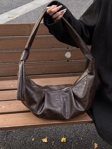 Retro dark brown slouchy hobo bag in soft leather finish on a wooden bench with autumn leaves