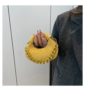 Detalle del bolso de media luna en ante amarillo con cadena gruesa de metal dorado y herrajes
