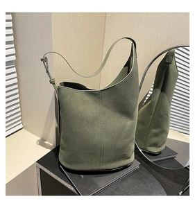 Detail view of the olive green minimalist bucket bag with adjustable strap on a display stand