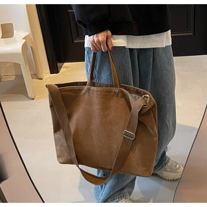 Detail view of large brown canvas tote bag with adjustable shoulder strap and metal rivets