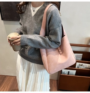 Model wearing a dusty pink matte faux leather hobo shoulder bag in a cozy library setting