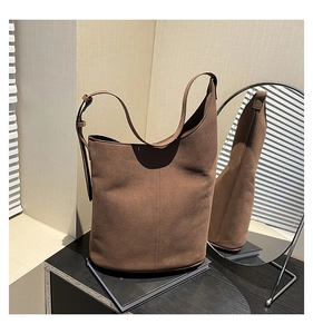 Detail of adjustable strap and vertical stitching on dark brown suede bucket bag
