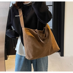 Brown canvas tote bag detail showing adjustable long strap and comfortable top handles
