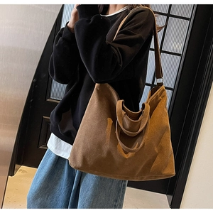 Brown canvas tote bag with long straps shown on shoulder for daily commute use