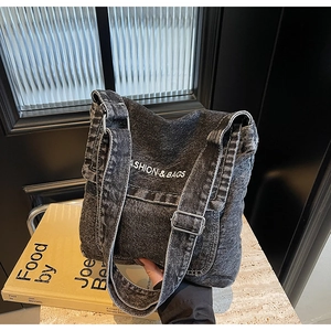 Dettaglio della borsa a tracolla in denim grigio scuro con cuciture bianche e fibbie