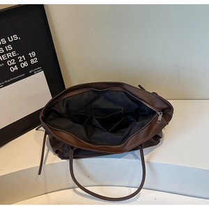 Vue intérieure du sac cabas marron montrant la doublure noire avec poches zippées et fentes