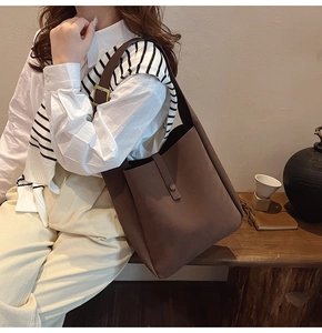 Detail view of deep brown matte tote bag showing adjustable copper buckle and suede texture