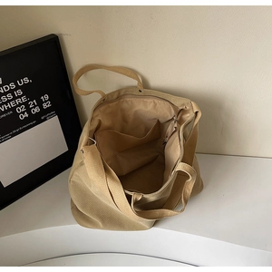 Detail shot of beige canvas tote bag showing top zipper closure and interior pocket