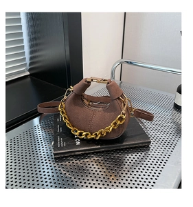 Detalle de bolso medialuna en ante marrón oscuro con una cadena decorativa dorada gruesa