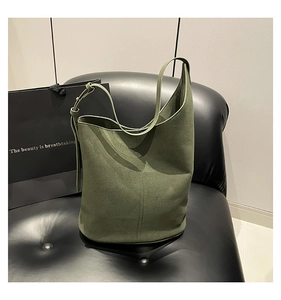 Detailed texture of forest green suede bucket bag with adjustable leather strap
