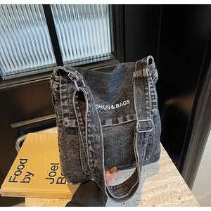 Dettaglio della borsa a tracolla in denim nero lavato con ricamo bianco ricamato