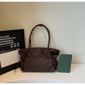 Détail du sac de voyage marron foncé montrant le cordon latéral et la texture du cuir