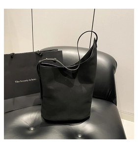 Detail of minimalist black bucket bag featuring matte leather and adjustable shoulder strap