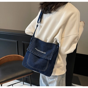 Dettaglio della borsa a tracolla in denim blu scuro con stampa FASHION & BAGS bianca