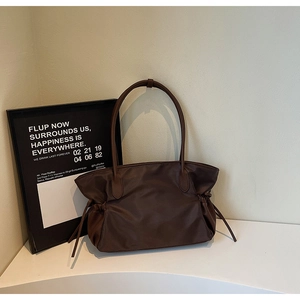 Détails latéraux du sac fourre-tout marron foncé avec plis à cordon et poignées en cuir chic