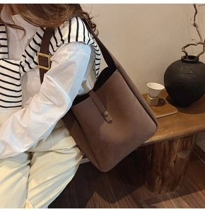 Brown matte tote bag with wide strap and golden buckle in minimalist lifestyle setting