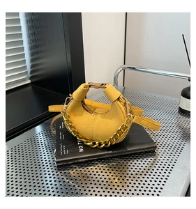 Detalle del bolso medialuna de ante amarillo jengibre con cadena dorada y hebilla