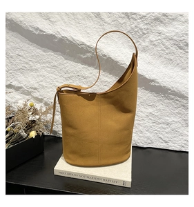 Detail of caramel bucket bag with adjustable strap on a minimalist stone background