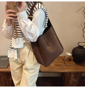 Brown leather tote bag with adjustable strap shown in a warm lifestyle setting