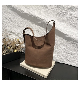 Detail of dark brown suede bucket bag with vertical stitching on minimalist art books