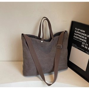 Close-up of thick canvas tote bag with adjustable wide strap and metal rivets detail