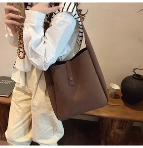 Detailed macro view of dark brown suede tote bag with decorative strap and matte texture